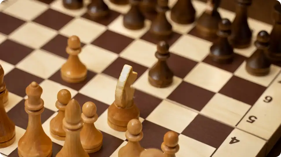 Houten schaakstukken gerangschikt op een klassiek schaakbord tijdens een strategisch bordspel.