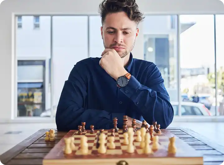 Jonge man die zich concentreert op het schaakbord terwijl hij zijn volgende strategische zet plant.